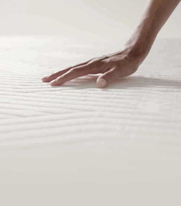 Hand die op een tempur matras duwt en de veerbaarheid van het materiaal illustreert.