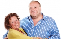 Een man en vrouw poseren samen voor een foto en lachen naar de camera. 